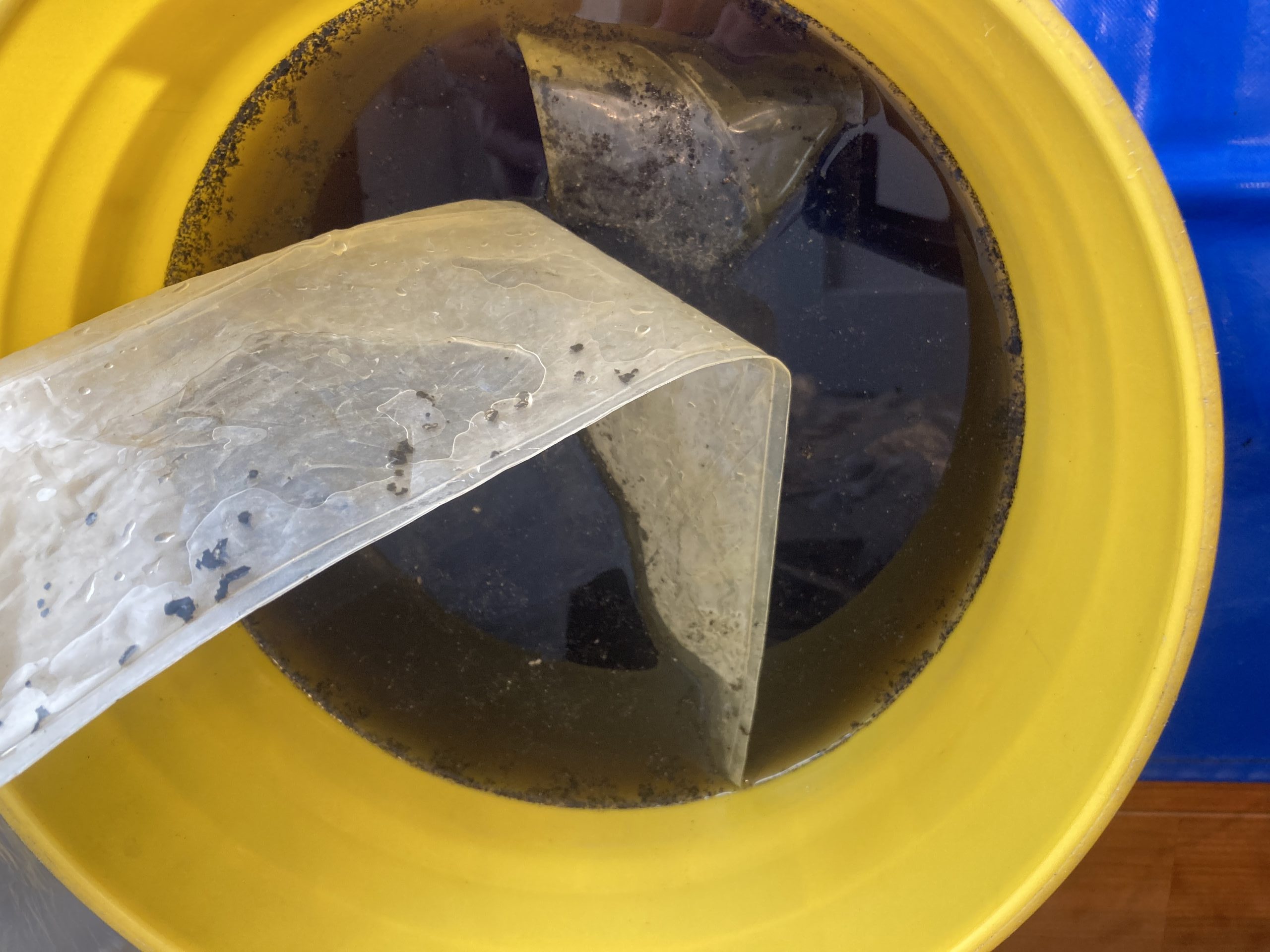 0年分の汚れが混ざった真っ黒な汚水。ファン内部に蓄積したカビ・ホコリが洗浄水に溶け出し、バケツの底が見えないほど。